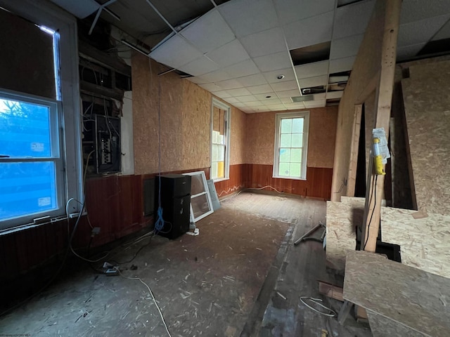 misc room featuring a drop ceiling and wooden walls