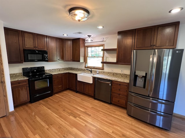 kitchen featuring open shelves, light wood-style floors, a sink, and black appliances
