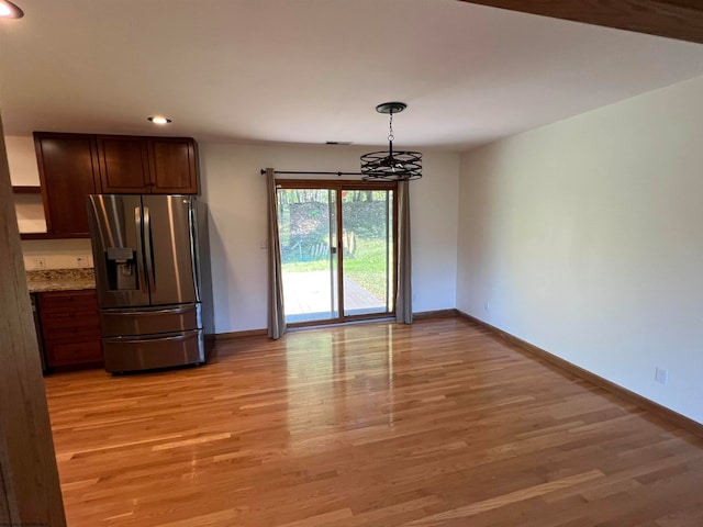 kitchen featuring hanging light fixtures, stainless steel fridge with ice dispenser, an inviting chandelier, and light wood-type flooring