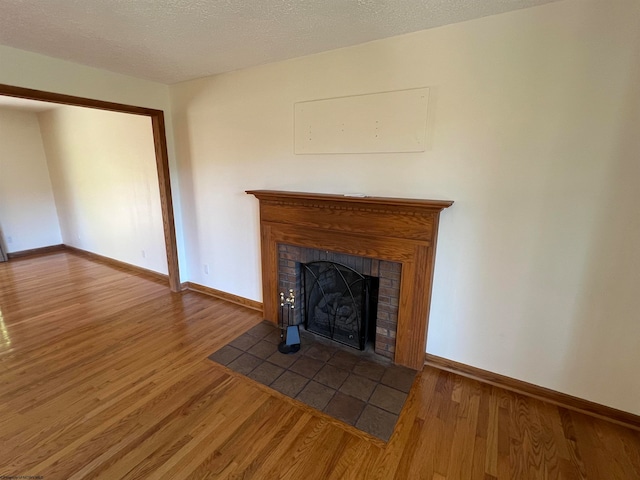 unfurnished living room with hardwood / wood-style flooring, a fireplace, and a textured ceiling