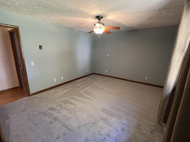 spare room with light colored carpet, baseboards, a ceiling fan, and a textured ceiling