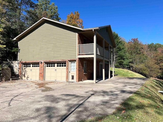 view of side of home featuring a garage and a balcony