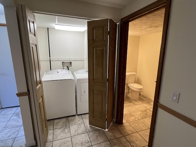 clothes washing area with a textured ceiling, independent washer and dryer, and laundry area