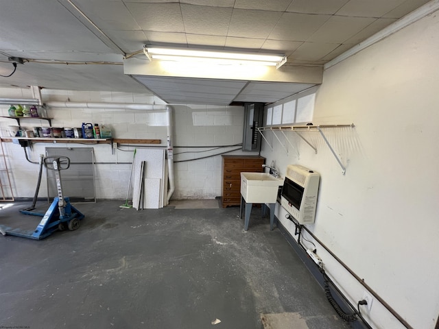 below grade area with heating unit, concrete block wall, and a sink