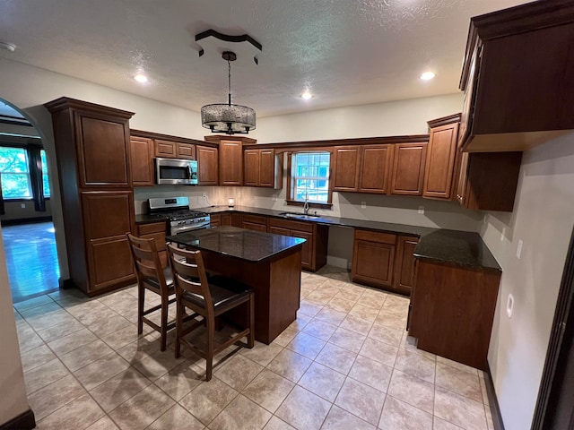 kitchen with a center island, dark stone countertops, sink, appliances with stainless steel finishes, and a textured ceiling