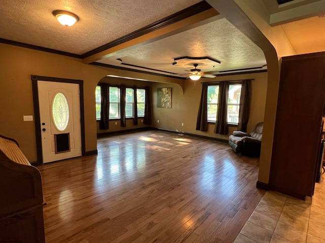 foyer with light wood-type flooring, beamed ceiling, ceiling fan, and a textured ceiling