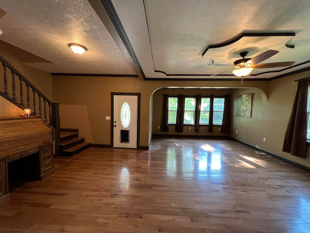 entrance foyer featuring wood-type flooring, ceiling fan, crown molding, and a textured ceiling