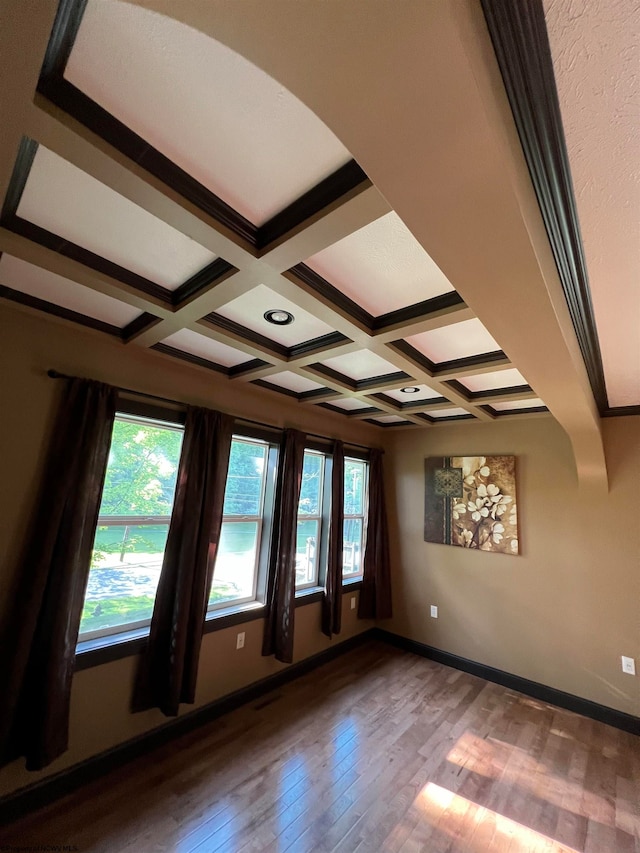 spare room featuring beamed ceiling, coffered ceiling, and hardwood / wood-style flooring