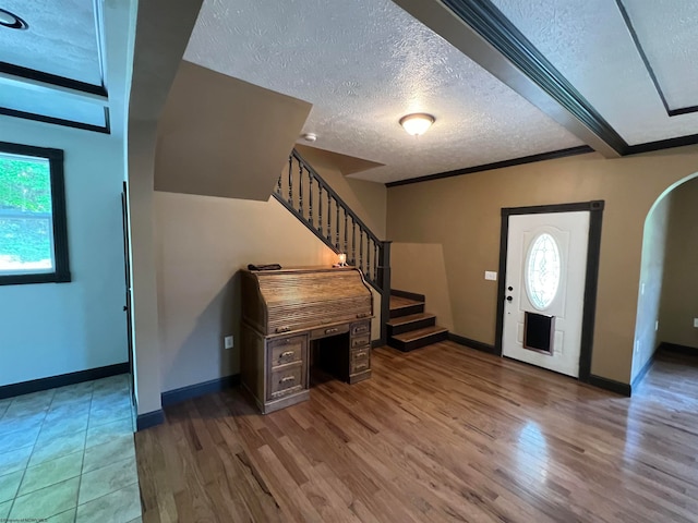 foyer entrance with wood-type flooring, a textured ceiling, and a wealth of natural light