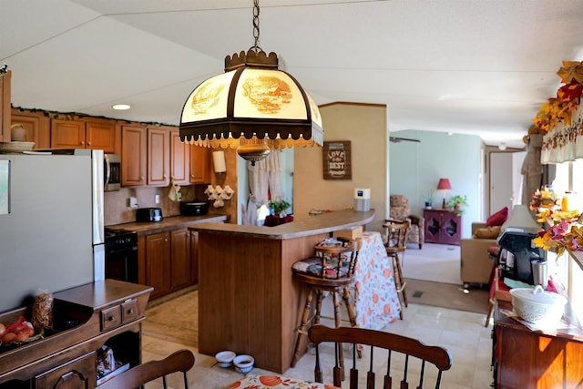 kitchen with white refrigerator, kitchen peninsula, decorative light fixtures, a breakfast bar, and black stove