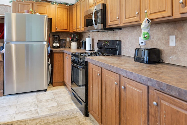 kitchen featuring stainless steel appliances, light tile patterned floors, and decorative backsplash