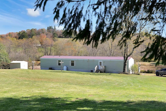 rear view of house with a storage shed and a yard