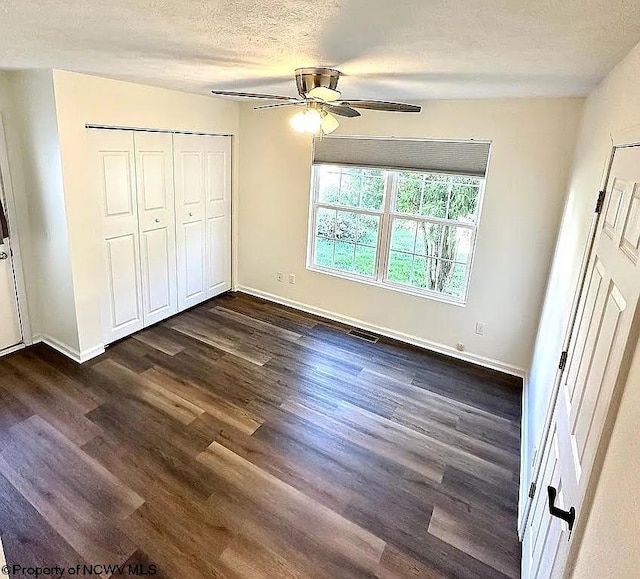 unfurnished bedroom with a closet, a textured ceiling, dark wood-type flooring, and ceiling fan