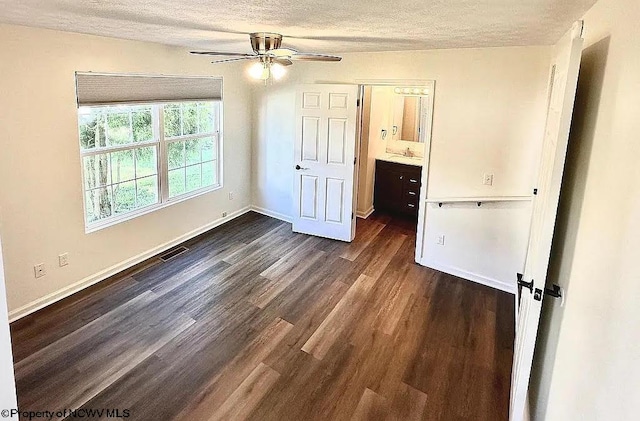 unfurnished bedroom featuring dark wood-type flooring, ceiling fan, a textured ceiling, and ensuite bath