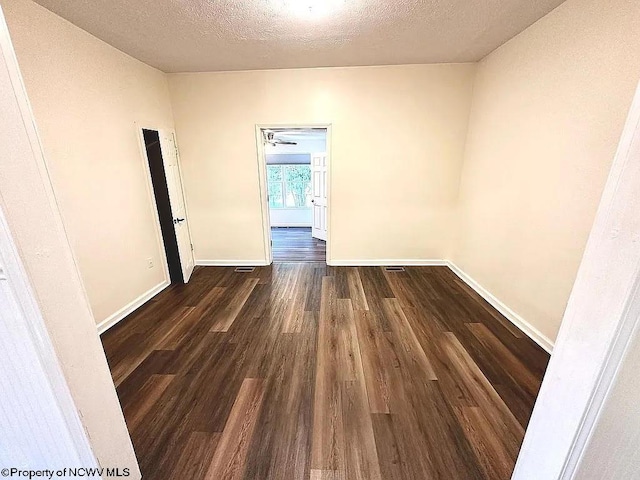 empty room featuring a textured ceiling and dark hardwood / wood-style flooring