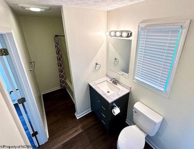 bathroom with a textured ceiling, hardwood / wood-style floors, toilet, a shower with curtain, and vanity