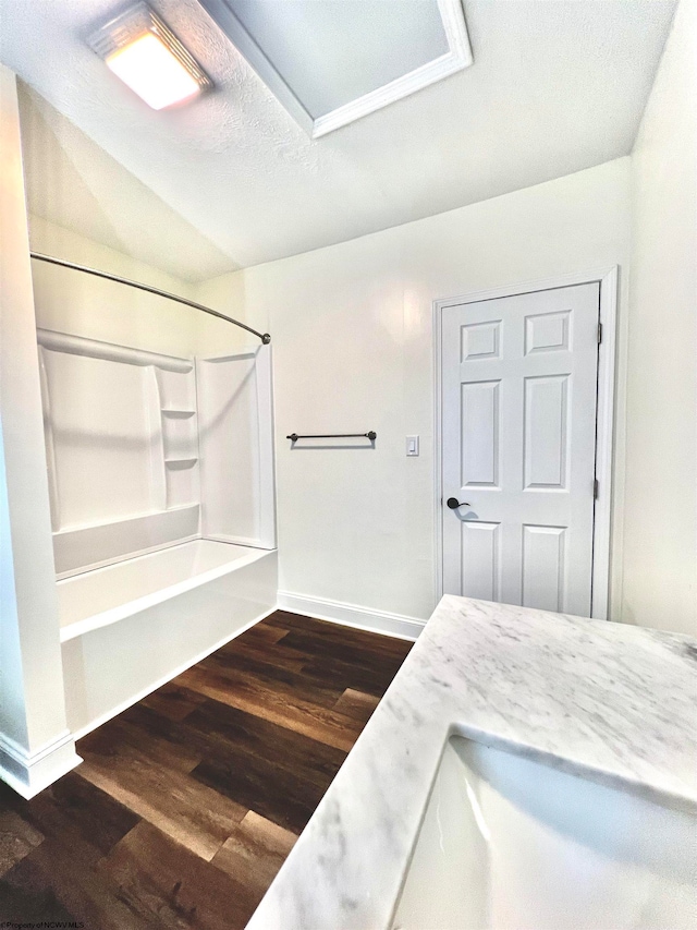 bathroom with  shower combination, a textured ceiling, hardwood / wood-style floors, lofted ceiling, and vanity