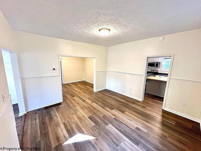 empty room with wood-type flooring and a textured ceiling