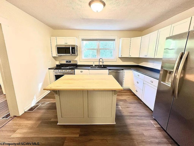 kitchen featuring white cabinets, appliances with stainless steel finishes, dark hardwood / wood-style floors, sink, and butcher block countertops