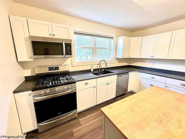 kitchen featuring hardwood / wood-style flooring, sink, white cabinets, appliances with stainless steel finishes, and a textured ceiling