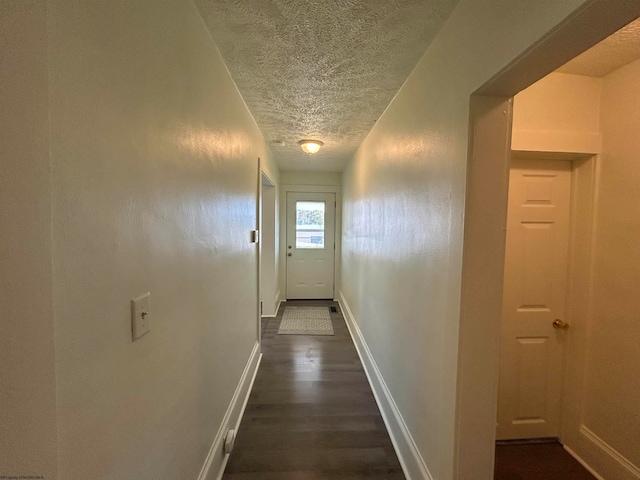 corridor with dark hardwood / wood-style floors and a textured ceiling