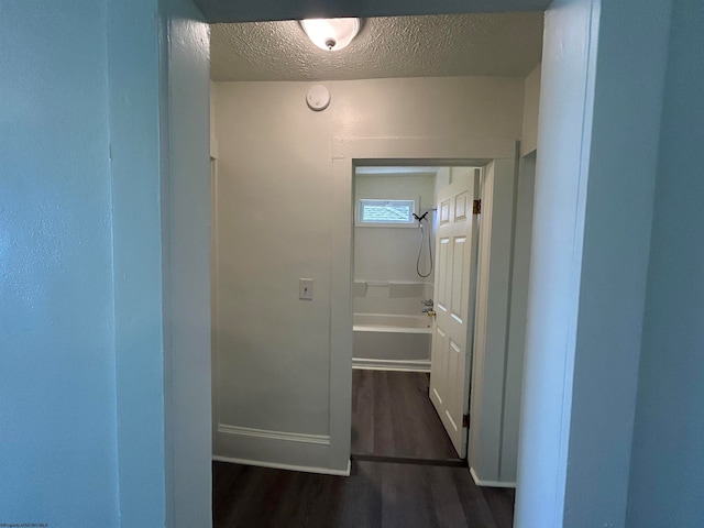 corridor featuring dark wood-type flooring and a textured ceiling