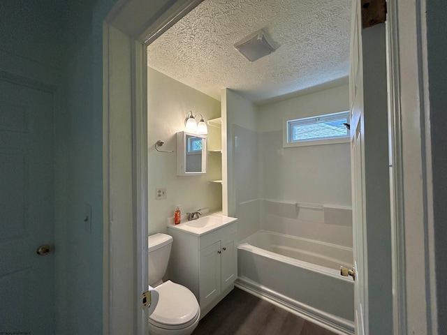 bathroom featuring vanity, toilet, a textured ceiling, a tub to relax in, and hardwood / wood-style floors