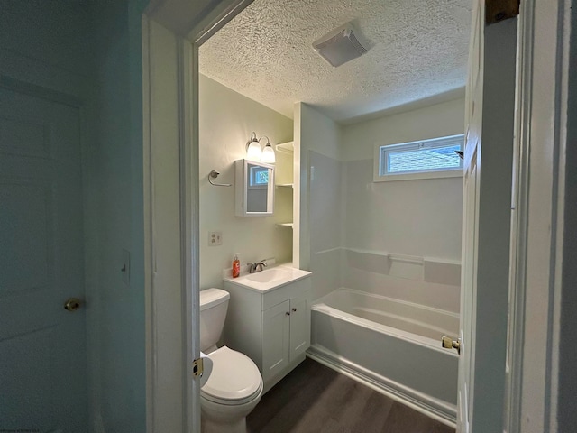 bathroom featuring toilet, a bathing tub, hardwood / wood-style flooring, vanity, and a textured ceiling