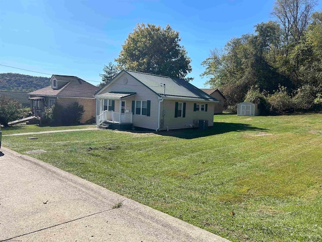 view of front of home with central AC unit, a front lawn, and a shed