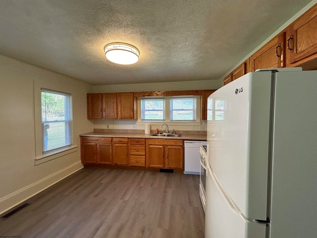 kitchen with a textured ceiling, light hardwood / wood-style flooring, sink, and white appliances