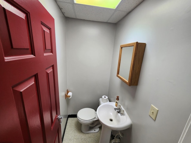 bathroom with toilet, a paneled ceiling, and sink