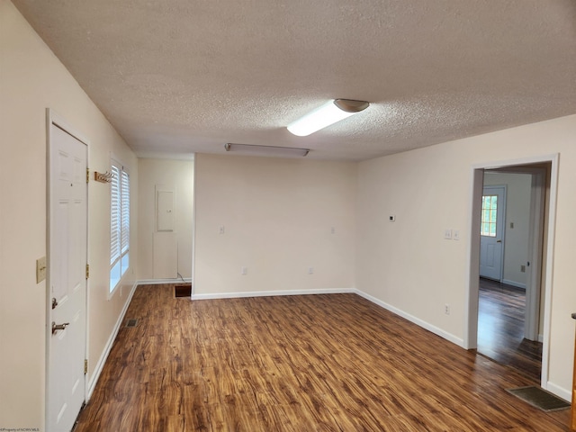 empty room with dark wood-type flooring and a textured ceiling