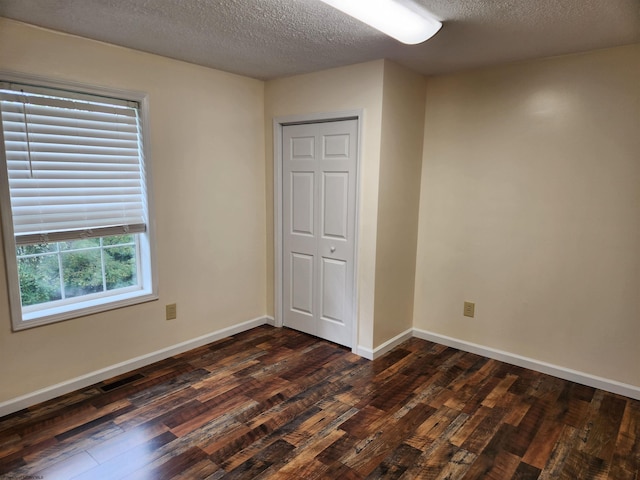 unfurnished bedroom with dark wood-type flooring, a closet, and a textured ceiling