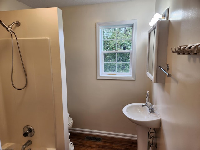 bathroom featuring bathtub / shower combination, hardwood / wood-style floors, a textured ceiling, and toilet