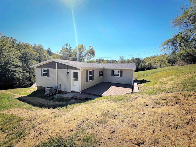 back of house featuring central AC unit, a wooden deck, and a lawn