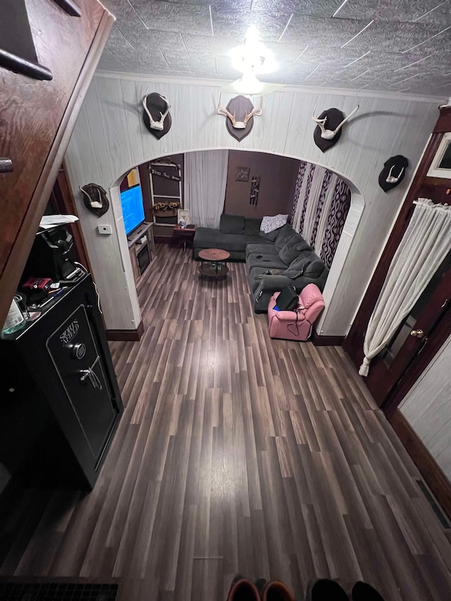 living room with dark wood-type flooring, wooden walls, and a textured ceiling