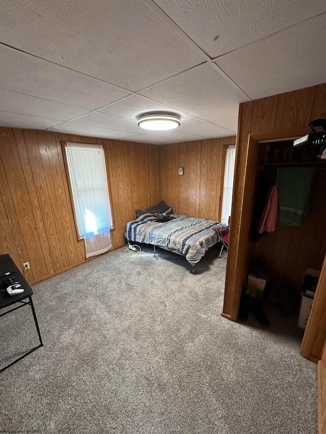 carpeted bedroom featuring wooden walls