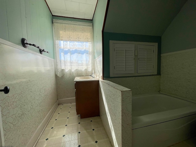 bathroom featuring lofted ceiling, a washtub, and vanity