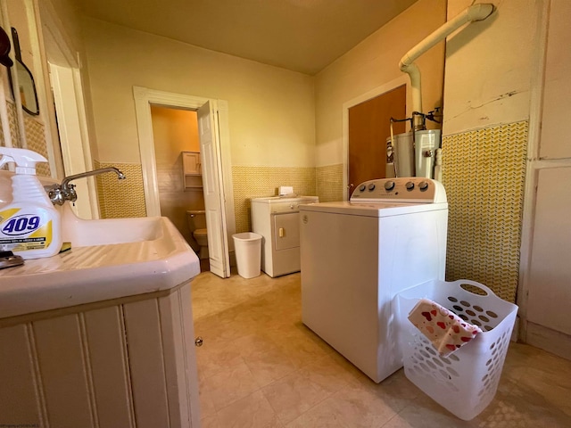 laundry room featuring water heater, tile walls, and washing machine and clothes dryer