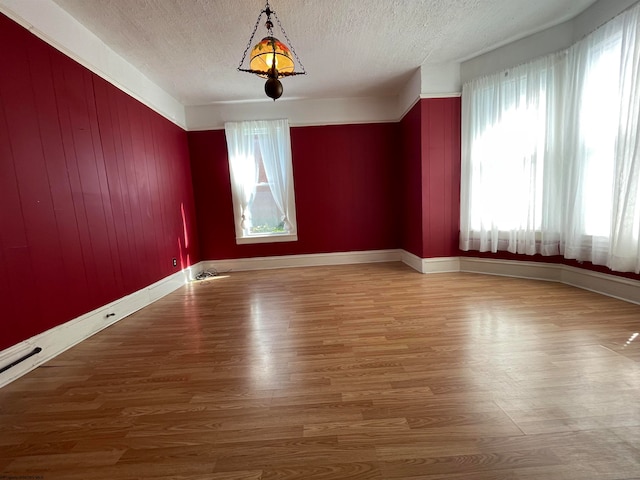 spare room featuring a textured ceiling, plenty of natural light, and hardwood / wood-style floors