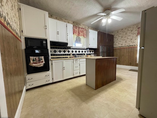 kitchen featuring ceiling fan, tasteful backsplash, wooden walls, white cabinetry, and black appliances