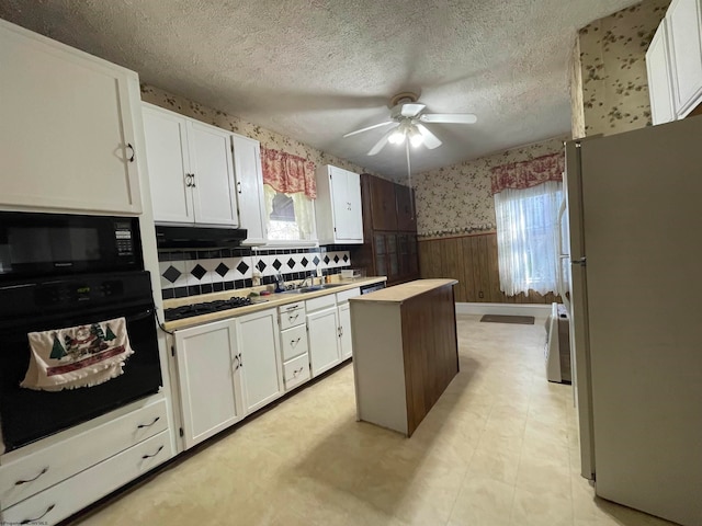 kitchen featuring decorative backsplash, white cabinets, black appliances, and a center island