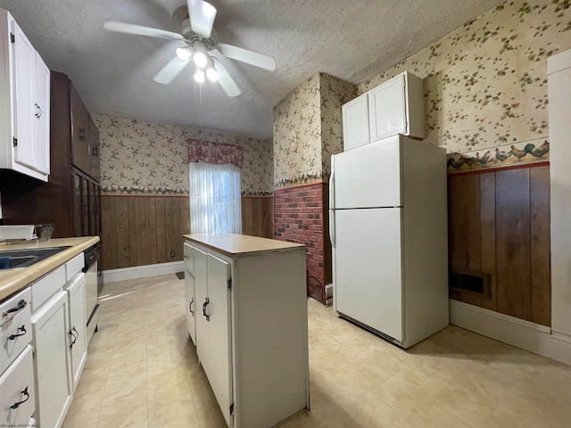 kitchen featuring a textured ceiling, white cabinetry, white appliances, and a kitchen island