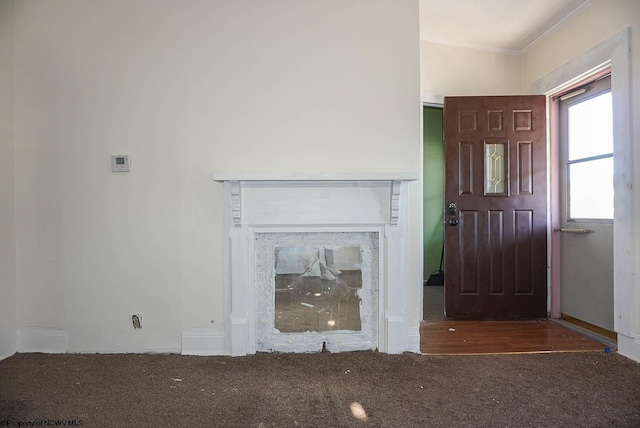 unfurnished living room featuring ornamental molding, lofted ceiling, and dark colored carpet