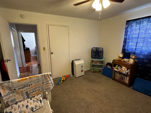 game room with carpet, ceiling fan, and a textured ceiling