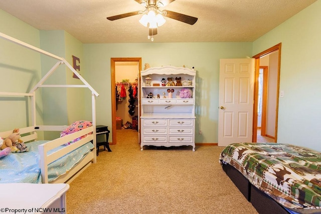 carpeted bedroom featuring ceiling fan, a spacious closet, a textured ceiling, and a closet