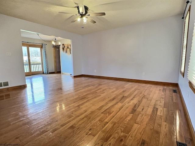 spare room with ceiling fan with notable chandelier and hardwood / wood-style flooring