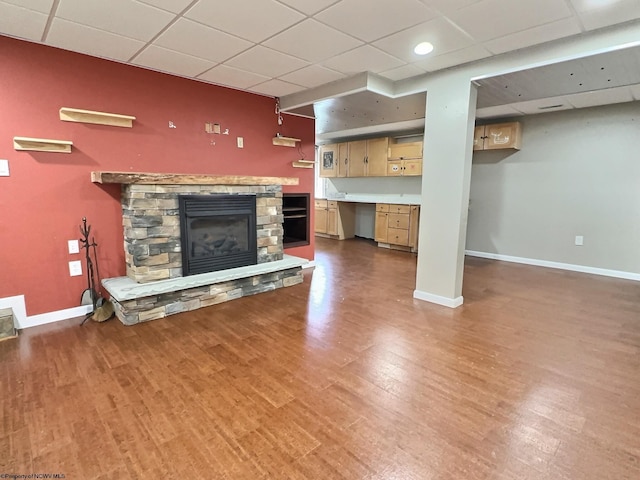 unfurnished living room featuring a fireplace, dark hardwood / wood-style flooring, and a drop ceiling