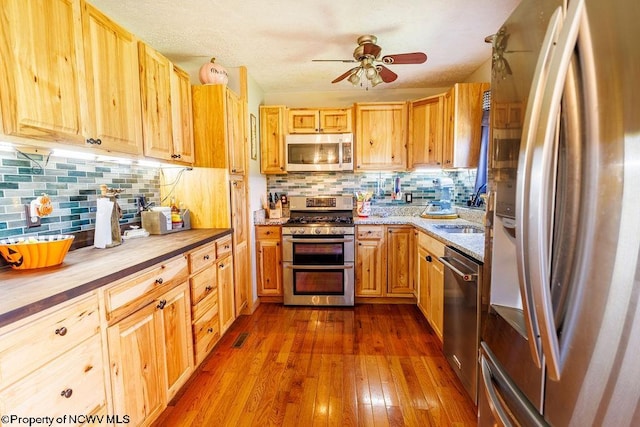 kitchen with decorative backsplash, stainless steel appliances, sink, hardwood / wood-style flooring, and butcher block counters