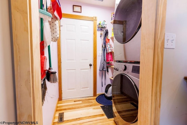 clothes washing area featuring hardwood / wood-style flooring and stacked washer and dryer